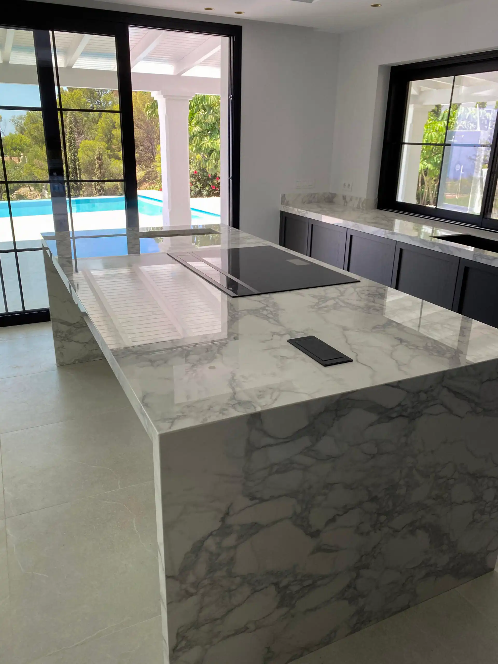 Isla de cocina con encimera de mármol y ventanas de perfil negro